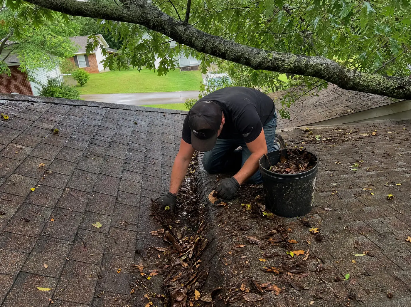 Roofer clearing debris from a valley during an annual maintenance visit in Springfield MO