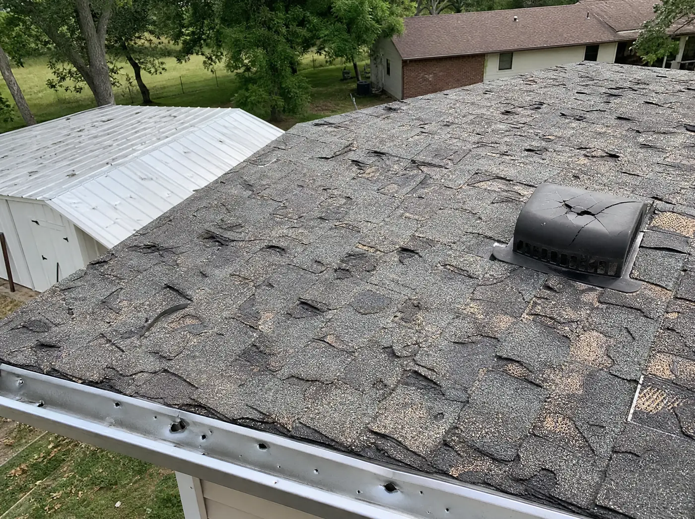 Roofer inspecting severe hail damage on a Willard MO home roof